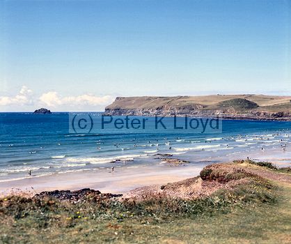 Polzeath Cornwall view of surf (with surfboarders) and sandy beach from clifftop