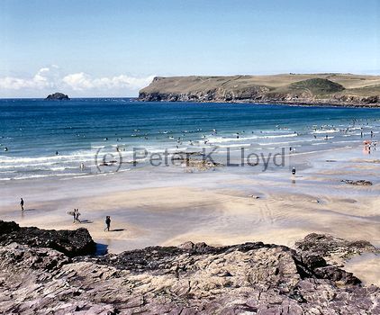 Polzeath Cornwall view of surf (with surfboarders) and sandy beach from clifftop